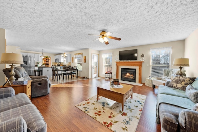 living room featuring dark hardwood / wood-style flooring, a textured ceiling, plenty of natural light, and ceiling fan