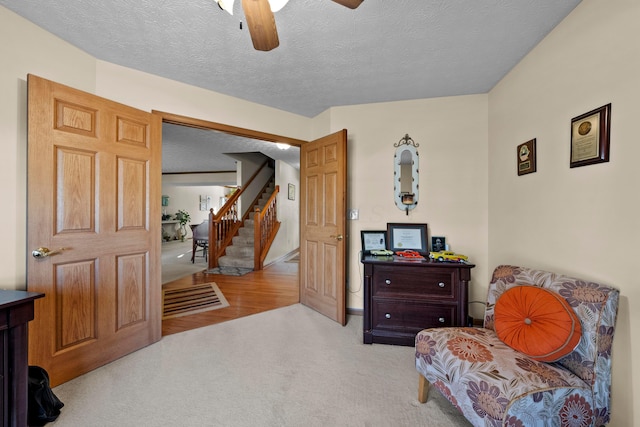 sitting room featuring ceiling fan, light colored carpet, and a textured ceiling