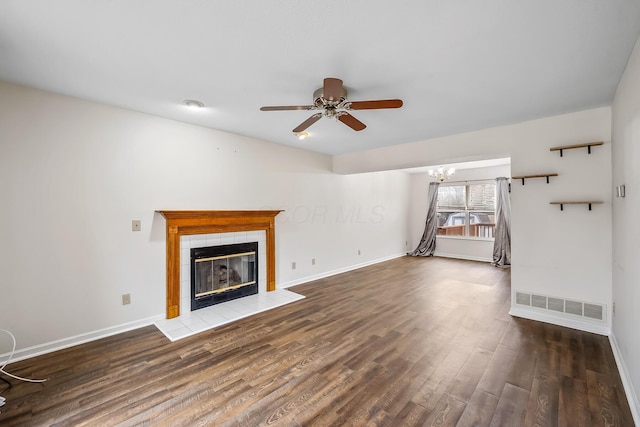 unfurnished living room with ceiling fan with notable chandelier, a fireplace, and dark hardwood / wood-style flooring