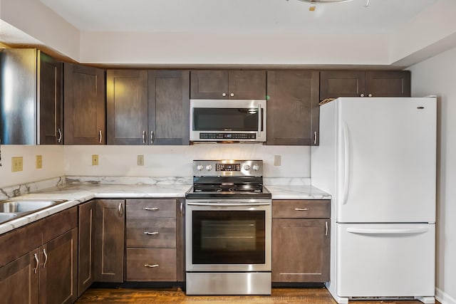 kitchen featuring light stone countertops, dark brown cabinets, and stainless steel appliances