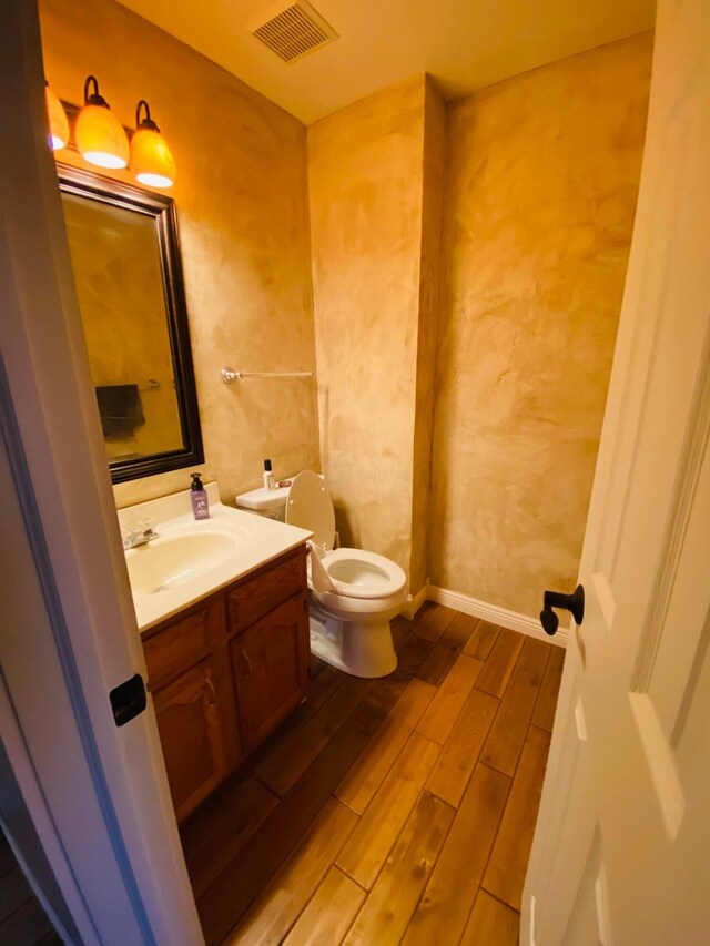 bathroom with hardwood / wood-style flooring, vanity, and toilet