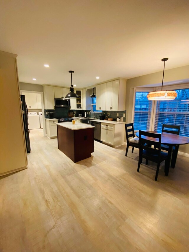 kitchen with stainless steel appliances, white cabinetry, a center island, and pendant lighting