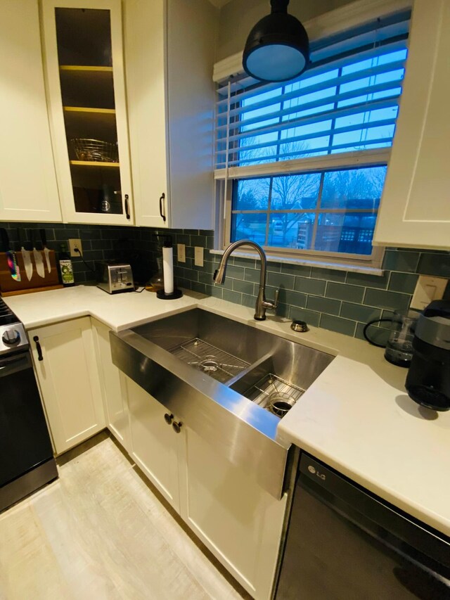 kitchen featuring white cabinetry, dishwasher, tasteful backsplash, and stove