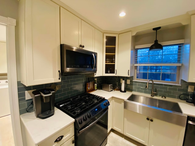 kitchen featuring appliances with stainless steel finishes, sink, hanging light fixtures, and white cabinets