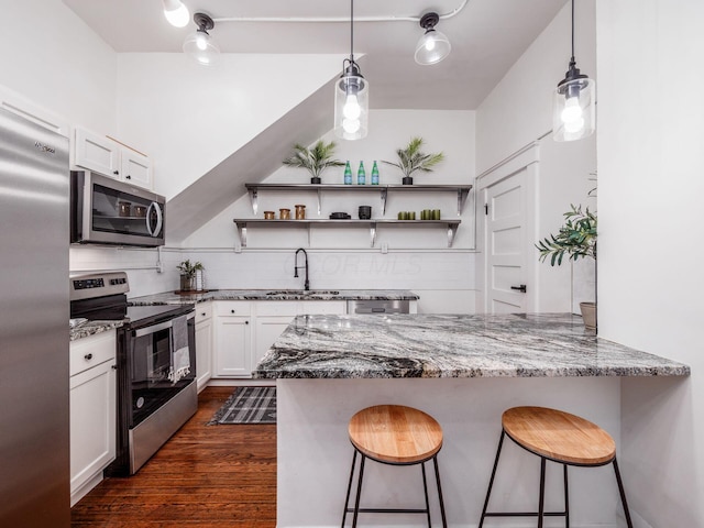 kitchen featuring a kitchen bar, sink, appliances with stainless steel finishes, kitchen peninsula, and white cabinets