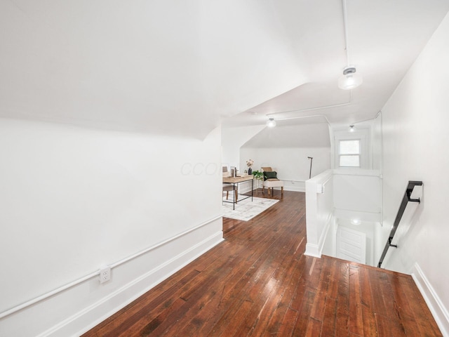 hall featuring dark wood-type flooring and vaulted ceiling