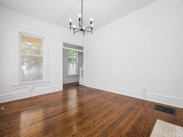 unfurnished dining area with a chandelier and dark hardwood / wood-style flooring