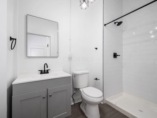 bathroom with vanity, toilet, and a tile shower