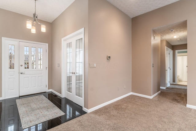 carpeted foyer featuring a chandelier and a textured ceiling