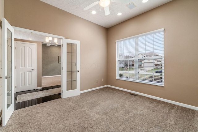 empty room featuring carpet floors, a textured ceiling, ceiling fan, and french doors