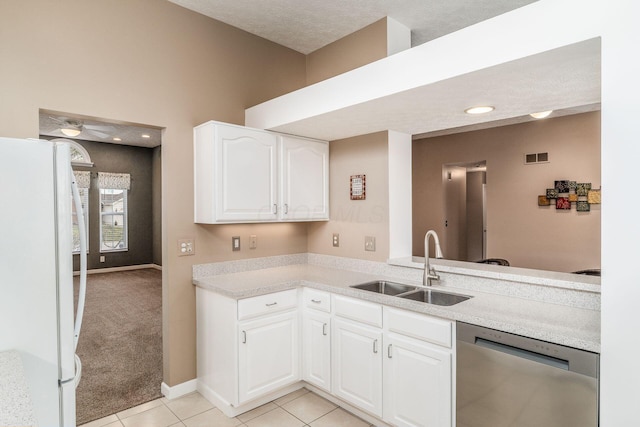 kitchen with sink, white cabinetry, light tile patterned floors, stainless steel dishwasher, and white fridge