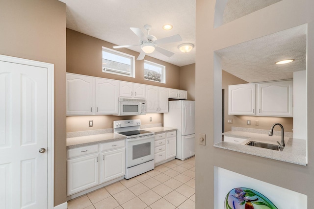 kitchen featuring sink, white appliances, light tile patterned floors, ceiling fan, and white cabinets