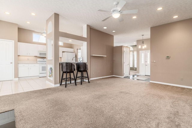 living room featuring a high ceiling, light carpet, a textured ceiling, and ceiling fan