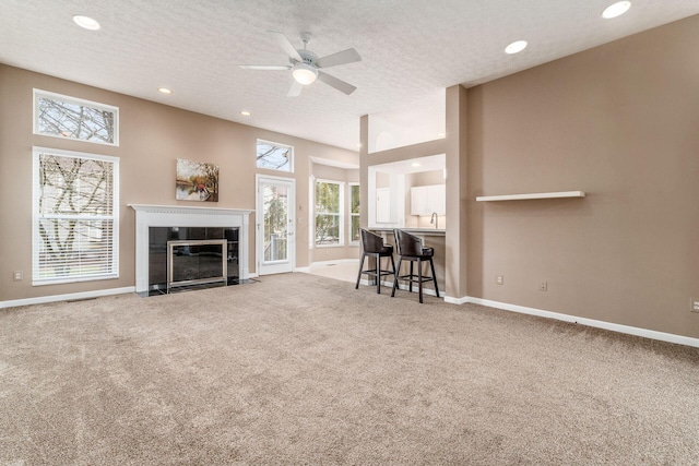 unfurnished living room with plenty of natural light, a tile fireplace, a textured ceiling, and carpet