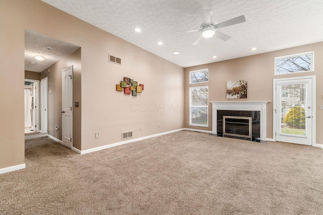 unfurnished living room featuring ceiling fan, carpet floors, and a textured ceiling