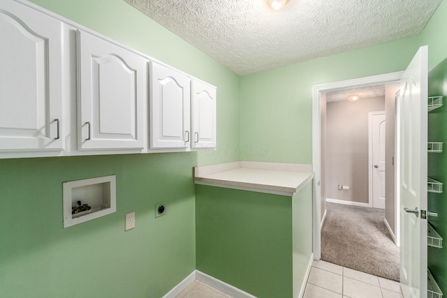 washroom featuring cabinets, light tile patterned floors, hookup for a washing machine, hookup for an electric dryer, and a textured ceiling