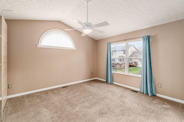 unfurnished room featuring ceiling fan, lofted ceiling, carpet, and a textured ceiling