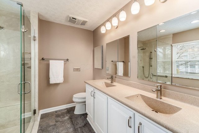 bathroom with vanity, a shower with shower door, toilet, and a textured ceiling