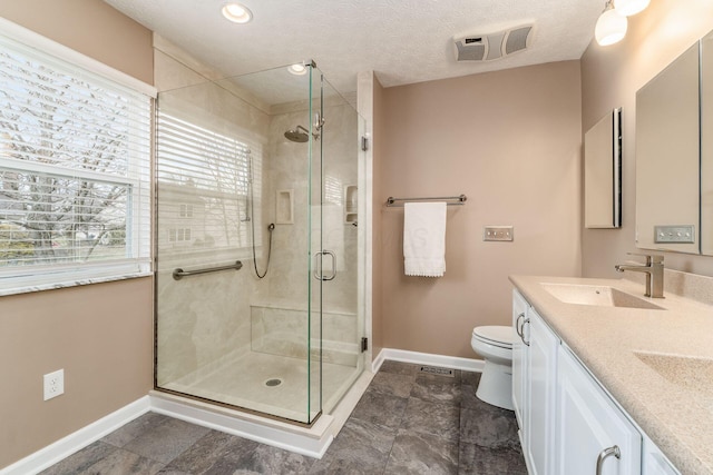 bathroom featuring an enclosed shower, vanity, plenty of natural light, and toilet