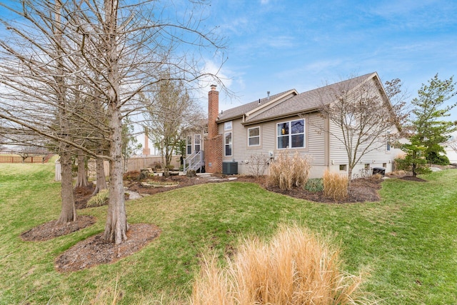 rear view of property with a lawn and central air condition unit