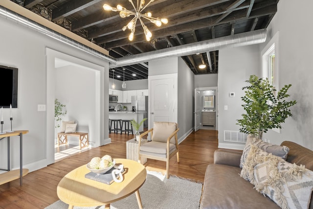 living room featuring sink, hardwood / wood-style flooring, a chandelier, and a towering ceiling