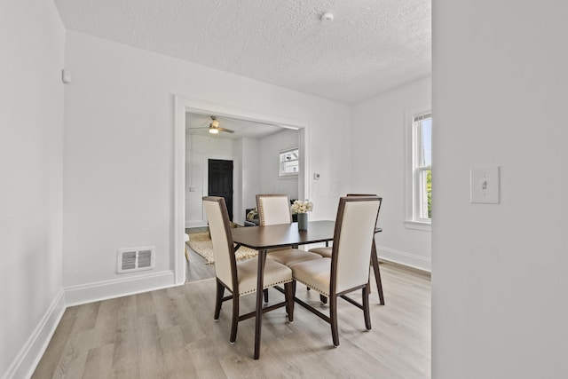 dining space with a textured ceiling and light wood-type flooring