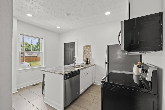 kitchen with range with electric stovetop, sink, white cabinets, stainless steel dishwasher, and light stone countertops