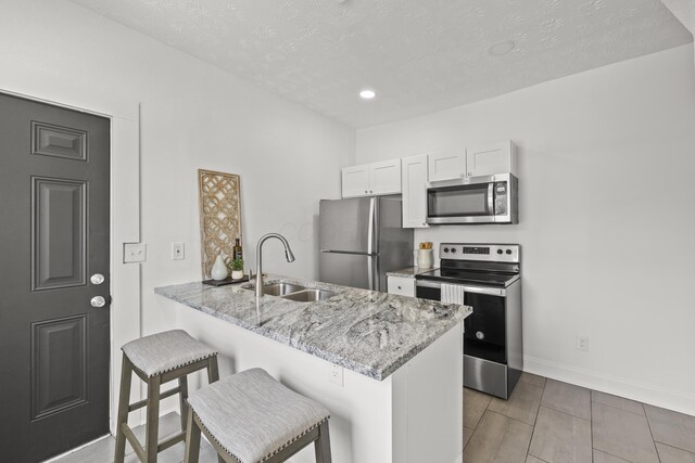 kitchen featuring sink, a breakfast bar, stainless steel appliances, white cabinets, and kitchen peninsula