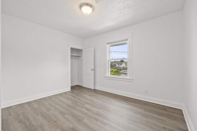 unfurnished bedroom featuring wood-type flooring, a textured ceiling, and a closet