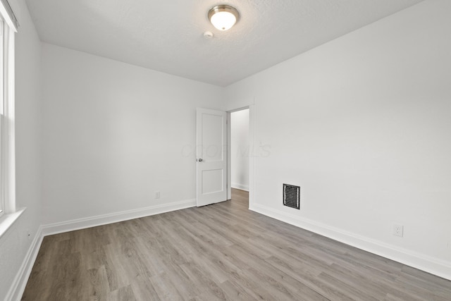 spare room featuring a textured ceiling and light wood-type flooring