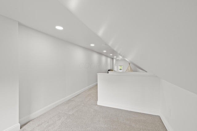 bonus room with light colored carpet and vaulted ceiling