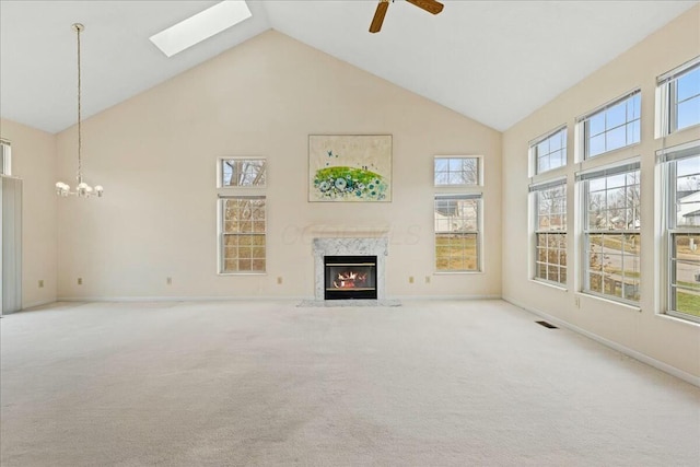 unfurnished living room with ceiling fan with notable chandelier, a high end fireplace, light carpet, and high vaulted ceiling