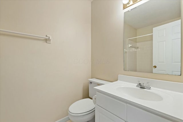 bathroom with tiled shower, vanity, and toilet