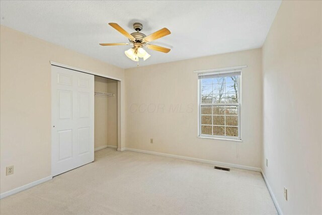 unfurnished bedroom featuring light colored carpet, ceiling fan, and a closet