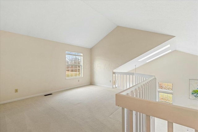 interior space with light colored carpet and vaulted ceiling with skylight