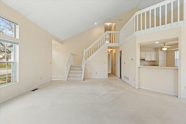 unfurnished living room with high vaulted ceiling, light colored carpet, and ceiling fan