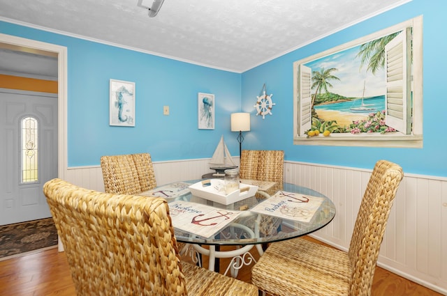 dining room with hardwood / wood-style floors, ornamental molding, and a textured ceiling