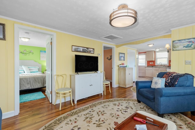 living room with ornamental molding, sink, and hardwood / wood-style floors