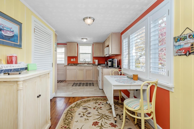 kitchen with white stove, sink, light brown cabinets, and light hardwood / wood-style flooring