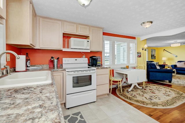 kitchen featuring sink, light brown cabinets, a textured ceiling, and white appliances