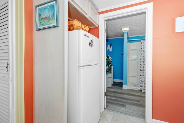 corridor featuring crown molding, a textured ceiling, and light tile patterned floors