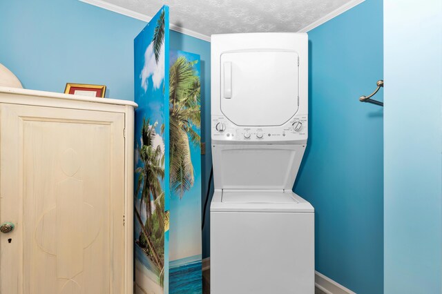 laundry area featuring stacked washer / dryer, crown molding, and a textured ceiling