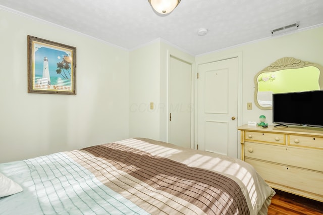 bedroom with crown molding and dark wood-type flooring