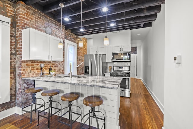 kitchen with white cabinetry, stainless steel appliances, kitchen peninsula, and sink