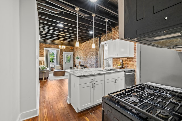 kitchen featuring sink, light stone counters, stainless steel dishwasher, brick wall, and white cabinets