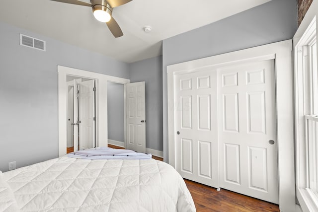 bedroom with dark wood-type flooring, ceiling fan, and a closet