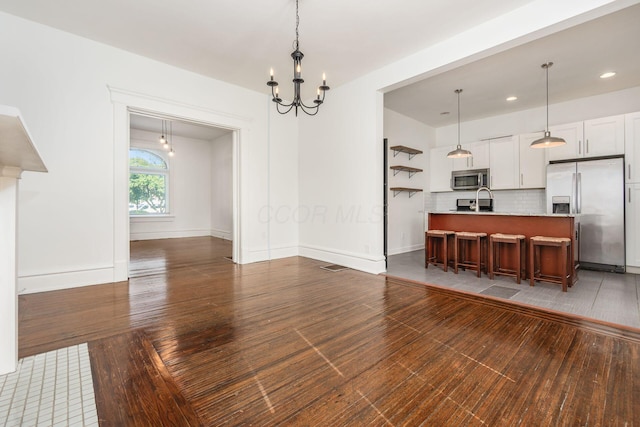 interior space featuring a breakfast bar, stainless steel appliances, white cabinets, a center island with sink, and dark hardwood / wood-style flooring