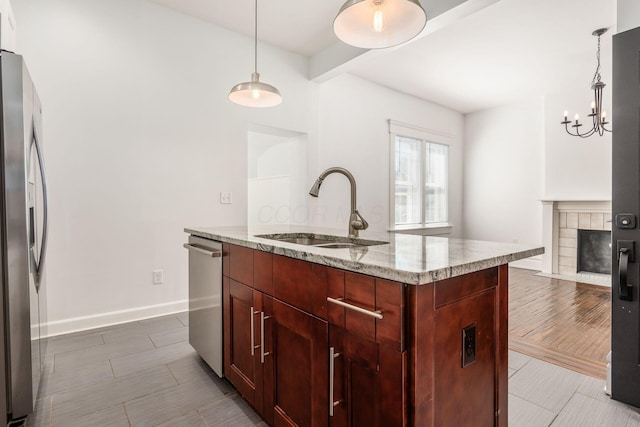 kitchen featuring pendant lighting, sink, stainless steel appliances, light stone countertops, and beam ceiling