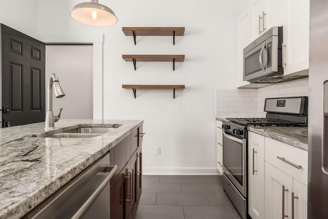 kitchen featuring sink, appliances with stainless steel finishes, white cabinetry, backsplash, and light stone counters