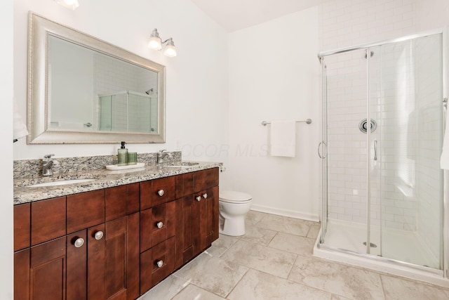 bathroom featuring vanity, a shower with shower door, and toilet